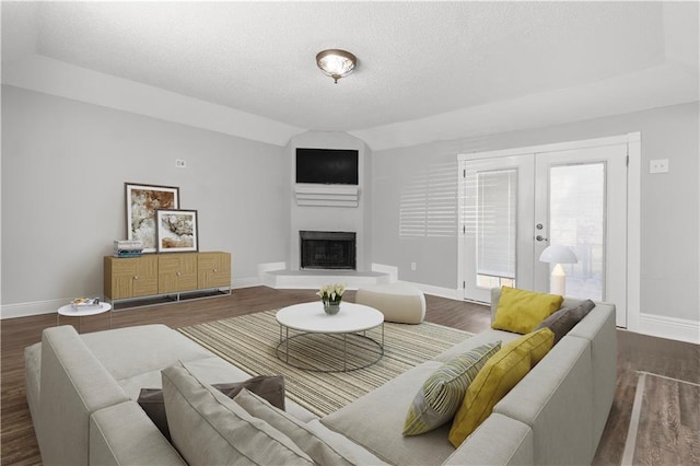 112 Napoleon Ave Unit 30, Slidell, LA 70460 - living room with wood finished floors, a textured ceiling, a fireplace with raised hearth, french doors, and vaulted ceiling