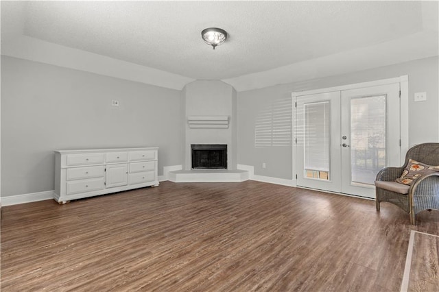 112 Napoleon Ave Unit 30, Slidell, LA 70460 - unfurnished living room with french doors, dark wood-type flooring, a fireplace with raised hearth, vaulted ceiling, and a textured ceiling