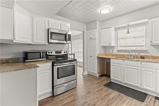 112 Napoleon Ave Unit 30, Slidell, LA 70460 - kitchen with appliances with stainless steel finishes, white cabinets, light wood finished floors, light stone countertops, and an ornate ceiling