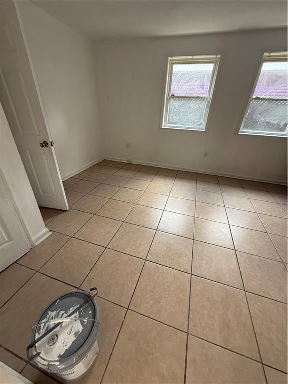 unfurnished room featuring plenty of natural light, light tile patterned flooring, and baseboards