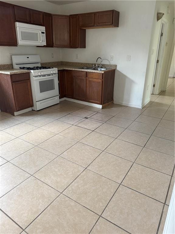 kitchen with white appliances, light tile patterned floors, a sink, baseboards, and light countertops