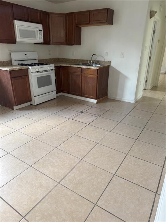 kitchen featuring white appliances, light tile patterned floors, baseboards, a sink, and light countertops