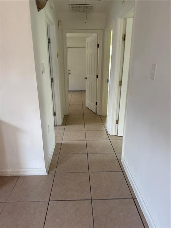 hallway with light tile patterned floors and baseboards