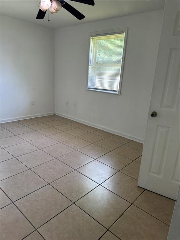 unfurnished room with a ceiling fan, light tile patterned flooring, and baseboards
