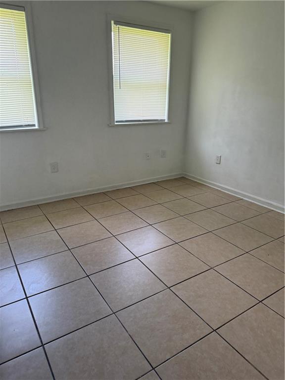 empty room featuring light tile patterned floors and baseboards
