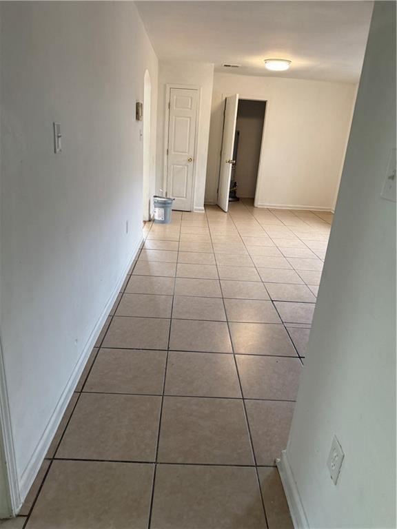 hallway with light tile patterned floors, arched walkways, and baseboards
