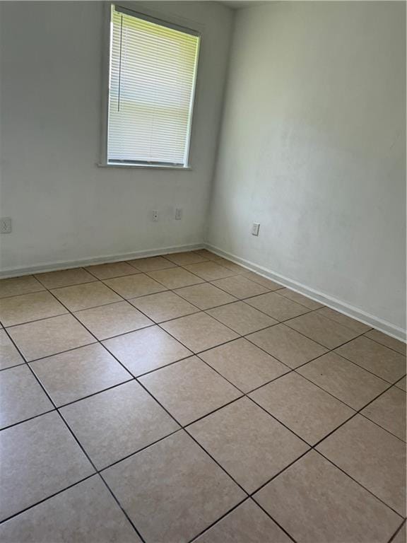 empty room featuring light tile patterned floors and baseboards