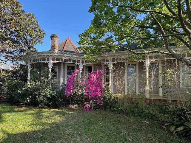 view of front facade with a chimney and a front yard