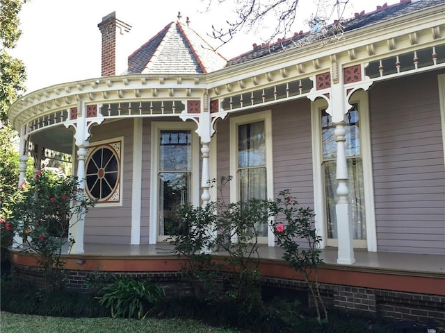 doorway to property with covered porch and a chimney