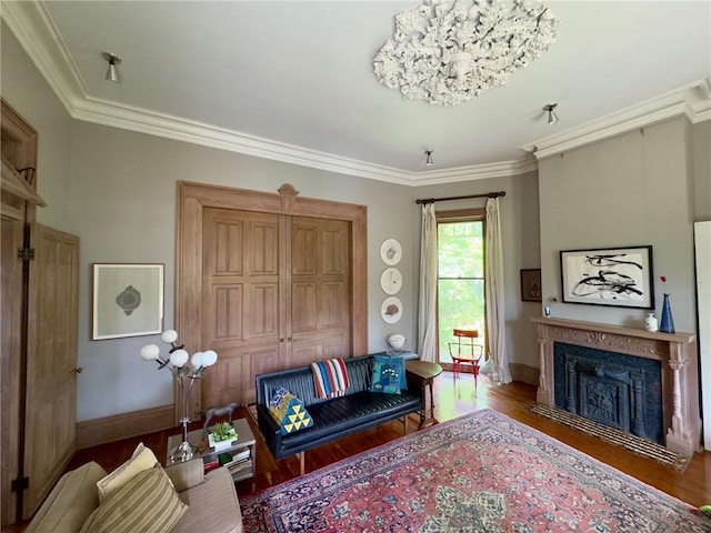 living area with wood finished floors, crown molding, a fireplace with flush hearth, and baseboards