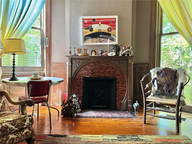 sitting room with hardwood / wood-style floors, wainscoting, and a brick fireplace