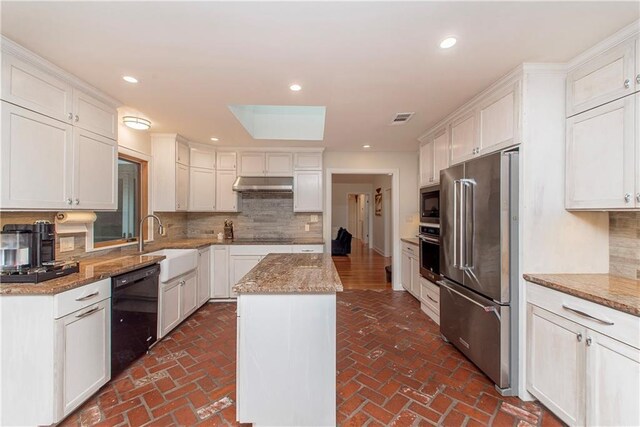 156 Oak Holw, Hammond, LA 70401 - kitchen featuring black appliances, under cabinet range hood, a sink, brick flooring, and tasteful backsplash