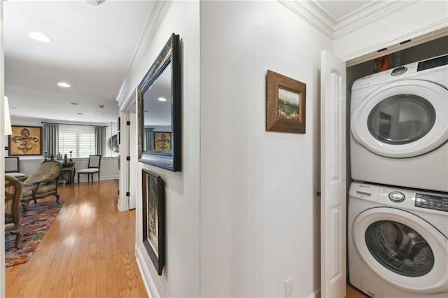 laundry room featuring stacked washer / dryer, crown molding, light wood finished floors, recessed lighting, and baseboards