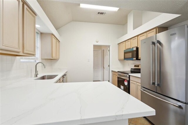 1155 Milan Dr, Mandeville, LA 70448 - kitchen with appliances with stainless steel finishes, light brown cabinetry, tasteful backsplash, lofted ceiling, and light stone counters