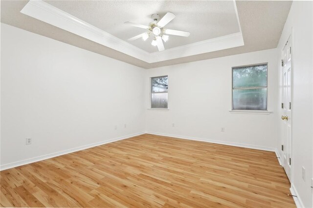 1155 Milan Dr, Mandeville, LA 70448 - spare room featuring a tray ceiling, crown molding, light wood finished floors, a ceiling fan, and a textured ceiling