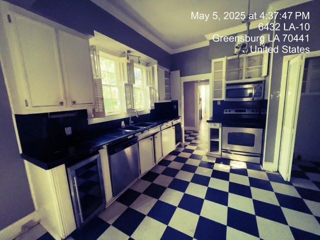 6396 10th Hwy, Greensburg, LA 70441 - kitchen with appliances with stainless steel finishes, a sink, tile patterned floors, white cabinetry, and dark countertops