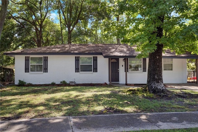 ranch-style house featuring a front yard, a carport, and brick siding