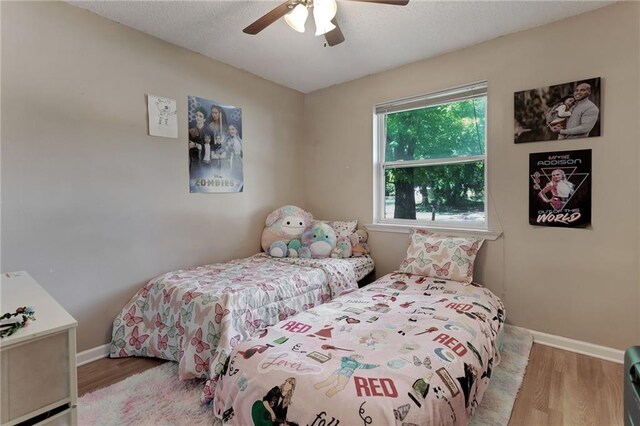 bedroom featuring wood finished floors, baseboards, and a ceiling fan