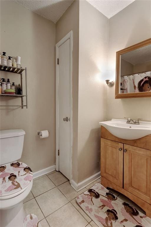 bathroom with toilet, tile patterned flooring, baseboards, vanity, and a textured ceiling