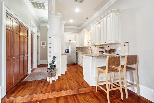 215 N Scott St, New Orleans, LA 70119 - kitchen with stainless steel fridge, wood finished floors, ornamental molding, a kitchen breakfast bar, and decorative backsplash