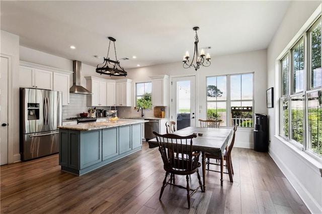 kitchen featuring stainless steel fridge with ice dispenser, wall chimney exhaust hood, healthy amount of natural light, and recessed lighting
