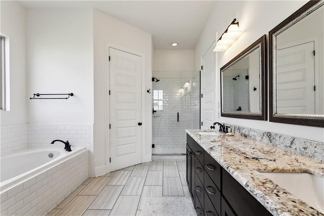full bathroom with a stall shower, double vanity, a bath, and recessed lighting