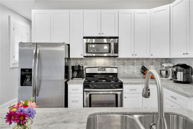 3310 Delachaise St, New Orleans, LA 70125 - kitchen with stainless steel appliances, a sink, white cabinets, and decorative backsplash