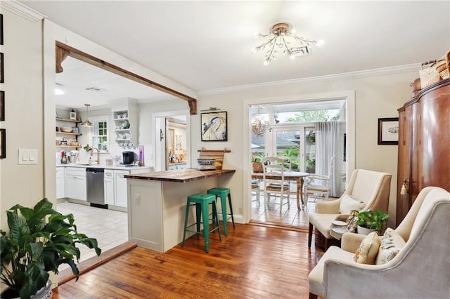 bar area with dishwasher, a chandelier, crown molding, a sink, and light wood-style floors