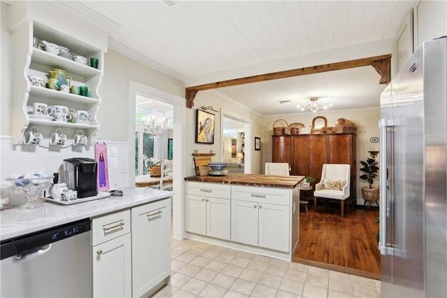 kitchen featuring appliances with stainless steel finishes, a chandelier, light tile patterned flooring, white cabinetry, and crown molding