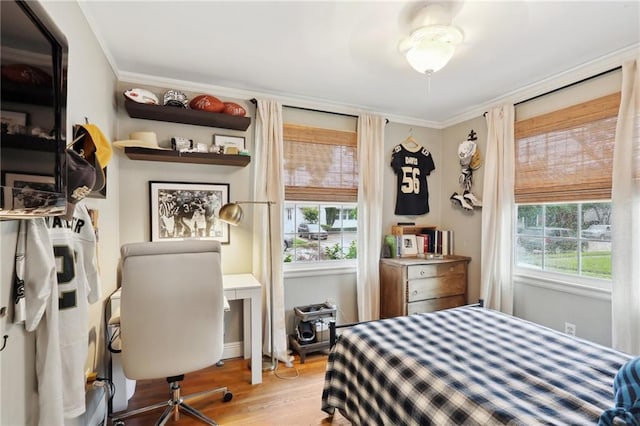 bedroom featuring multiple windows, ornamental molding, and wood finished floors