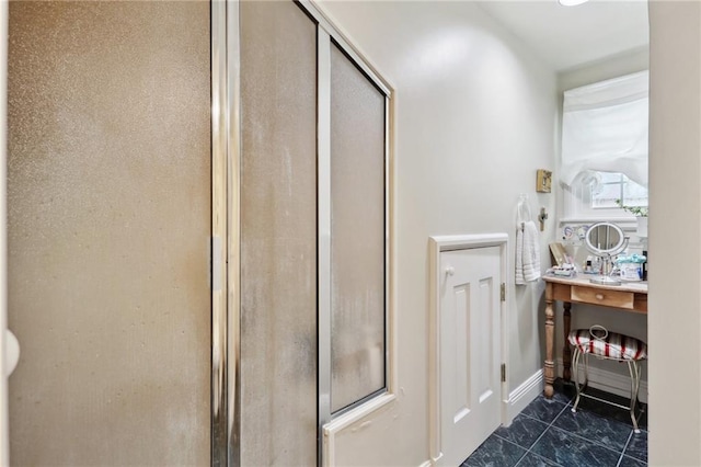 full bath with marble look tile flooring and a shower stall