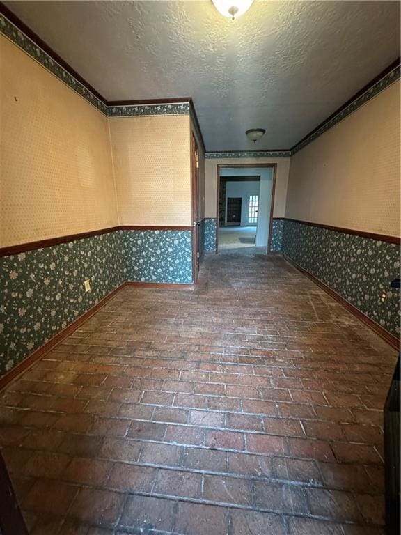 4408 Janice Ave, Metairie, LA 70003 - hall featuring wallpapered walls, baseboards, a textured ceiling, a wainscoted wall, and brick flooring