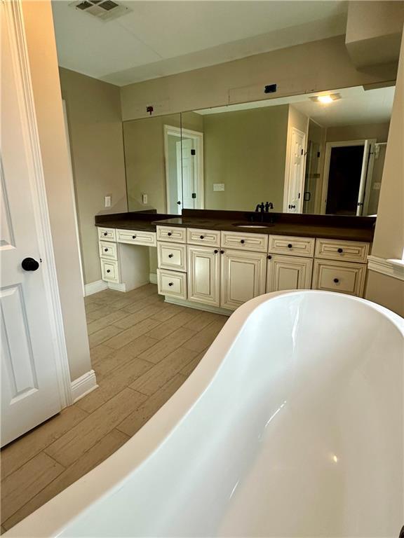 4408 Janice Ave, Metairie, LA 70003 - full bath featuring a soaking tub, wood finished floors, vanity, and baseboards