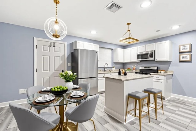 3017 Music St, New Orleans, LA 70122 - kitchen with appliances with stainless steel finishes, a sink, white cabinetry, a center island, and baseboards