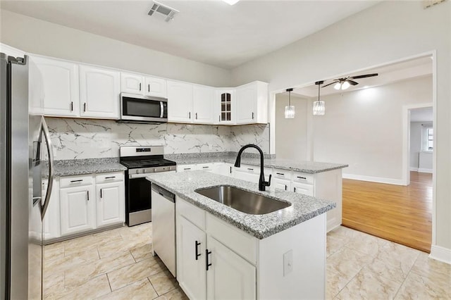 838 Jefferson St, Gretna, LA 70053 - kitchen with stainless steel appliances, a sink, ceiling fan, an island with sink, and white cabinetry