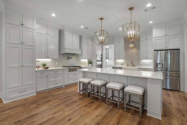 972 Camphill Dr, Abita Springs, LA 70420 - kitchen featuring appliances with stainless steel finishes, a sink, white cabinets, a breakfast bar area, and light countertops