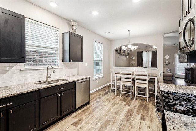 kitchen featuring stainless steel appliances, a sink, light wood finished floors, tasteful backsplash, and recessed lighting