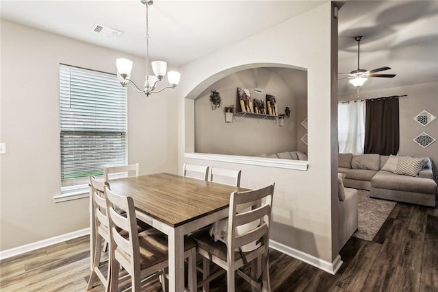 dining room featuring wood finished floors, ceiling fan, baseboards, a chandelier, and arched walkways
