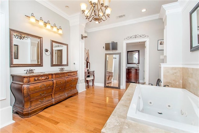 bathroom featuring a tub with jets, ornamental molding, a chandelier, wood finished floors, and double vanity