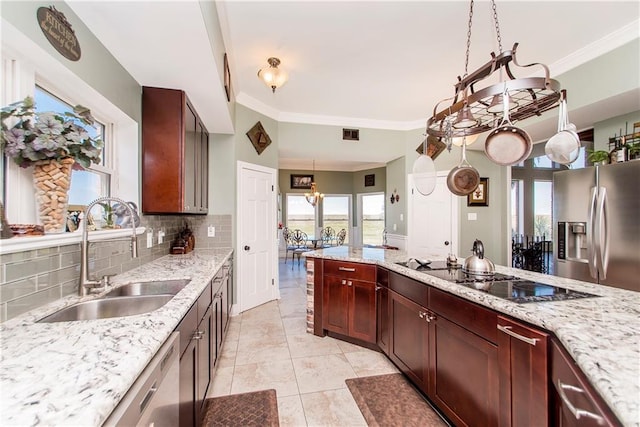 kitchen with a sink, appliances with stainless steel finishes, decorative backsplash, ornamental molding, and light stone counters