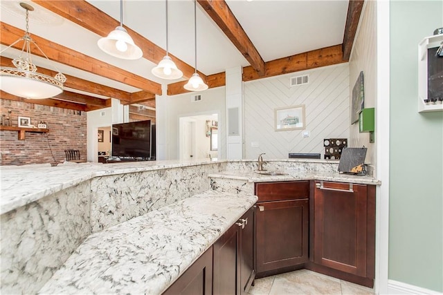 kitchen with beamed ceiling, a sink, light stone countertops, hanging light fixtures, and light tile patterned floors