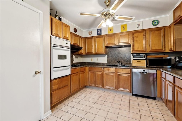 kitchen featuring stainless steel appliances, a warming drawer, brown cabinetry, a ceiling fan, and light tile patterned flooring