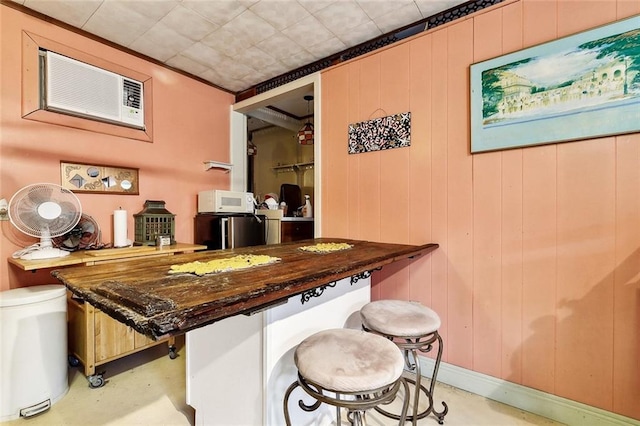 bar featuring white microwave, wooden walls, and concrete floors