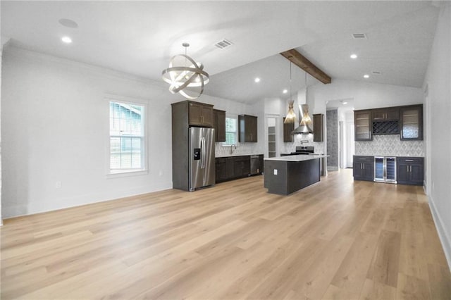 kitchen with stainless steel fridge, backsplash, light countertops, wall chimney exhaust hood, and open floor plan