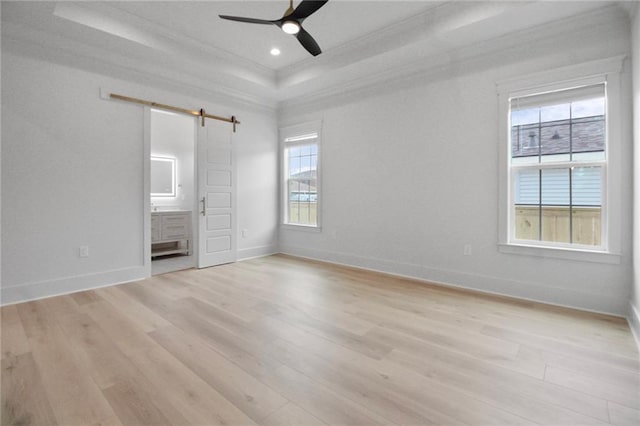 unfurnished bedroom with a barn door, multiple windows, crown molding, light wood-style flooring, and baseboards