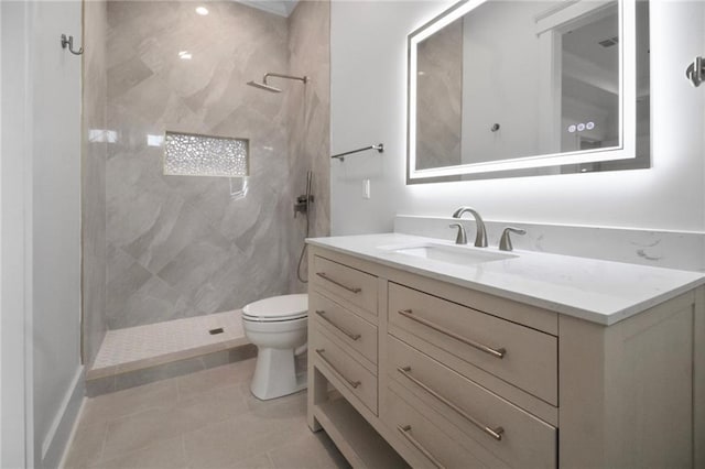bathroom with vanity, tiled shower, toilet, and tile patterned floors