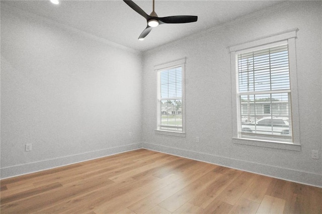 spare room featuring baseboards, light wood-style flooring, ceiling fan, and ornamental molding
