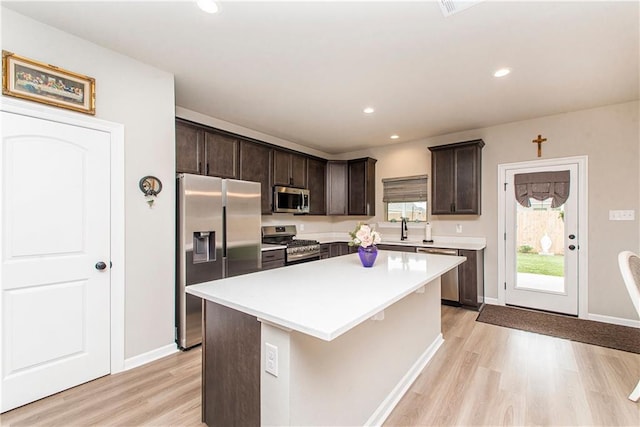 20452 Cornerstone Rd, Hammond, LA 70401 - kitchen with appliances with stainless steel finishes, light wood-style flooring, dark brown cabinets, a kitchen island, and light countertops
