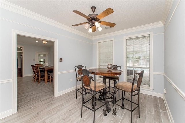 412 Magnolia Ln, Slidell, LA 70461 - dining area featuring light wood-type flooring, baseboards, ornamental molding, a ceiling fan, and a textured ceiling