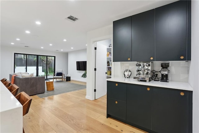 1712 Upperline St, New Orleans, LA 70115 - kitchen with dark cabinets, light wood-style flooring, light countertops, recessed lighting, and open floor plan